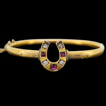 Load image into Gallery viewer, A yellow gold horseshoe bangle bracelet with rubies and diamonds, on a black background