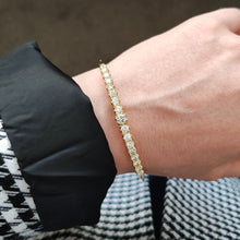 Load image into Gallery viewer, A yellow gold diamond bangle bracelet, modelled on a wrist