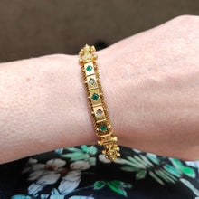 Load image into Gallery viewer, A yellow gold Etruscan style bangle bracelet set with emeralds and diamonds, modelled on a wrist