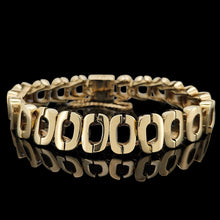 Load image into Gallery viewer, An oval link bracelet in yellow gold, on a black background