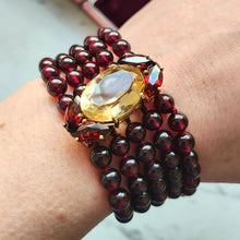 Load image into Gallery viewer, A five row round garnet bead bracelet with a citrine and garnet clasp in yellow gold, modelled on a wrist