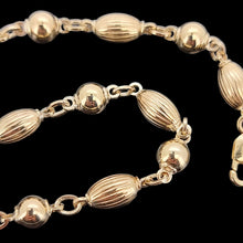 Load image into Gallery viewer, Gold bracelet with alternating round and oval beads on a black background