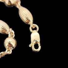 Load image into Gallery viewer, Close-up of a gold bracelet with a clasp on a black background
