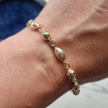 Load image into Gallery viewer, Gold bracelet on a wrist with a blurred background