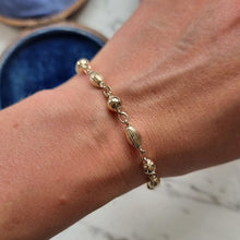 Load image into Gallery viewer, Gold bracelet on a wrist with a blurred background