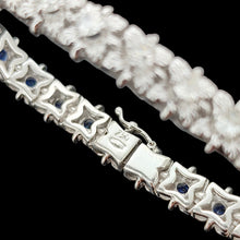Load image into Gallery viewer, A close-up of the clasp of a sapphire and diamond white gold line bracelet, stamped 750, on a black background