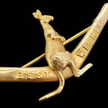 Load image into Gallery viewer, A boomerang shaped brooch with a kangaroo reading BEST WISHES, in yellow gold, on a black background