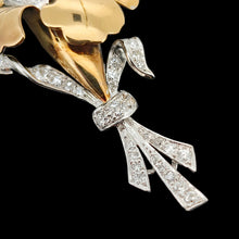 Load image into Gallery viewer, A two tone gold flower brooch with diamonds, on a black background