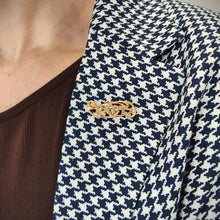 Load image into Gallery viewer, A yellow gold brooch with the word BABY written in pearls, modelled on the lapel of a houndstooth pattern jacket