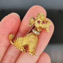 Load image into Gallery viewer, A yellow gold poodle dog brooch with ruby eyes and a diamond set collar, held in a hand