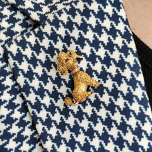 Load image into Gallery viewer, A yellow gold poodle dog brooch with ruby eyes and a diamond set collar, modelled on the lapel of a houndstooth print jacket