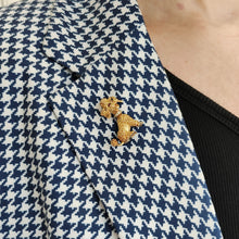 Load image into Gallery viewer, A yellow gold poodle dog brooch with ruby eyes and a diamond set collar, modelled on the lapel of a houndstooth print jacket