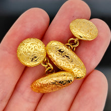 Load image into Gallery viewer, A pair of yellow gold engraved oval and round cufflinks, held in a hand
