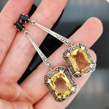 Load image into Gallery viewer, A pair of citrine, onyx and marcasite long drop earrings in silver, held in a hand