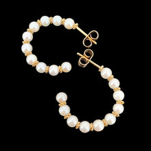 Load image into Gallery viewer, A pair of yellow gold pearl half hoop earrings with butterfly fittings, on a black background