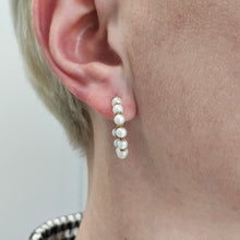 Load image into Gallery viewer, A yellow gold pearl half hoop earring, modelled in an ear