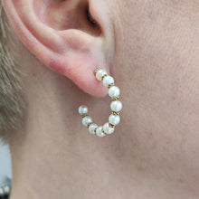Load image into Gallery viewer, A yellow gold pearl half hoop earring, modelled in an ear