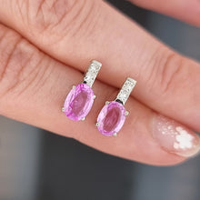 Load image into Gallery viewer, Pink sapphire and diamonds earrings held between fingers against a neutral background