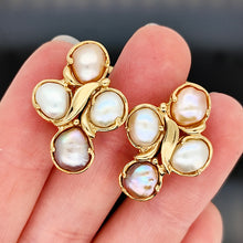Load image into Gallery viewer, A pair of pink and white pearl cluster earrings in yellow gold, held in a hand