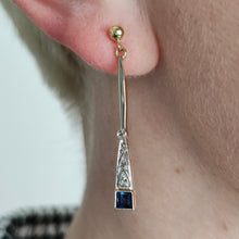Load image into Gallery viewer, A sapphire and diamond long drop earring in yellow and white gold, modelled in an ear