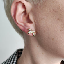 Load image into Gallery viewer, A yellow gold round diamond cross shaped stud earring, modelled in an ear