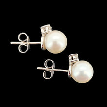 Load image into Gallery viewer, A pair of white pearl and round diamond stud earrings in white gold, on a black background