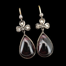Load image into Gallery viewer, A pair of pear shaped garnet and rose cut diamond earrings in gold and silver, on a black background