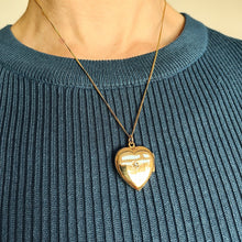 Load image into Gallery viewer, A yellow gold heart shaped locket with a diamond, modelled with a chain by a woman wearing a blue top