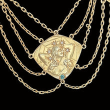 Load image into Gallery viewer, Gold necklace with a decorative pendant featuring a face and gemstones on a black background