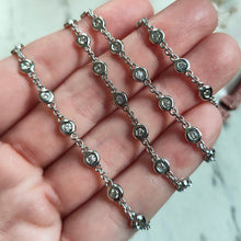 Load image into Gallery viewer, A white gold round diamond station necklace, held in a hand