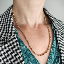 Load image into Gallery viewer, A yellow gold faceted link chain necklace, modelled by a woman wearing a green top and houndstooth print jacket