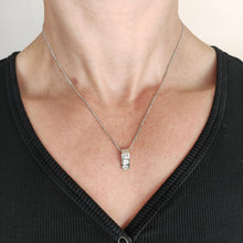 Load image into Gallery viewer, A brilliant and princess cut diamond pendant in platinum, with a white gold curb chain, modelled by a woman