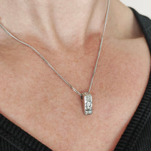 Load image into Gallery viewer, A brilliant and princess cut diamond pendant in platinum, with a white gold curb chain, modelled by a woman