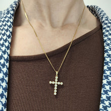 Load image into Gallery viewer, A round diamond cross pendant in yellow gold hung on a gold chain, modelled on a woman