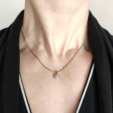 Load image into Gallery viewer, A flower shaped diamond cluster pendant in yellow gold and platinum, modelled on a gold chain by a woman