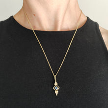 Load image into Gallery viewer, A yellow gold square sapphire and seed pearl pendant, with a chain, modelled by a woman wearing a black top