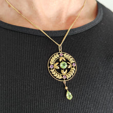 Load image into Gallery viewer, A peridot and amethyst yellow gold drop pendant, with a chain, modelled by a woman wearing a black top