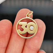 Load image into Gallery viewer, A yellow gold 30 pendant with a brilliant cut diamond, in a hand