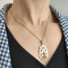 Load image into Gallery viewer, A white enamelled flower pendant, with a gold chain, modelled by a women