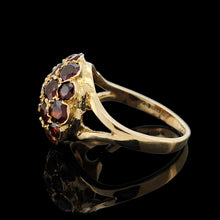 Load image into Gallery viewer, A round garnet domed cluster ring in yellow gold, against a black background