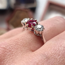 Load image into Gallery viewer, Close-up of a three stone ruby and diamond ring modelled on a finger