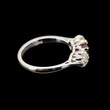 Load image into Gallery viewer, Side view of a three stone ruby and diamond ring on a black background