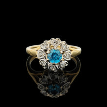 Load image into Gallery viewer, A blue zircon and diamond flower cluster ring in yellow and white gold, on a black background