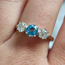 Load image into Gallery viewer, A three stone blue zircon and diamond ring in yellow and white gold, modelled on a hand