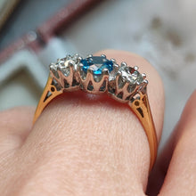 Load image into Gallery viewer, A three stone blue zircon and diamond ring in yellow and white gold, modelled on a hand