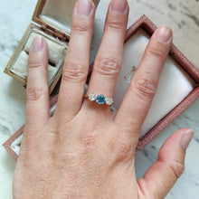 Load image into Gallery viewer, A three stone blue zircon and diamond ring in yellow and white gold, modelled on a hand