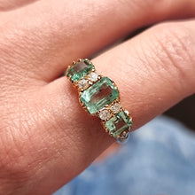 Load image into Gallery viewer, Ring with emerald and diamond stones on a finger against a blurred background
