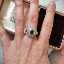 Load image into Gallery viewer, An oval sapphire and diamond cluster ring in yellow and white gold, modelled on a hand