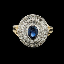 Load image into Gallery viewer, An oval sapphire and diamond cluster ring in yellow and white gold, on a black background