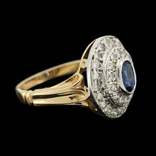 Load image into Gallery viewer, An oval sapphire and diamond cluster ring in yellow and white gold, on a black background